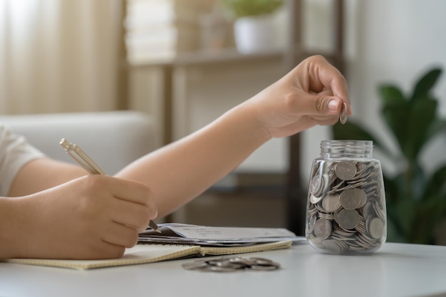 Woman with coins jar taking note to checklist expenses