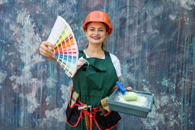 Photo woman with color swatch. shes in coverall and helmet posing on abstract background