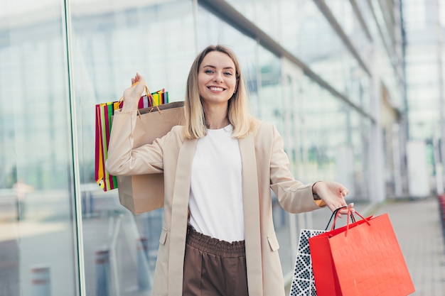 Woman with colored bags with goods near a modern shopping mall