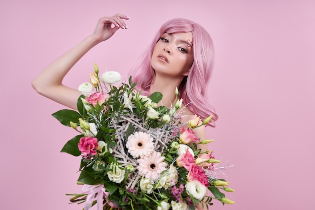 Woman with colored pink strong hair holds a bouquet of beautiful flowers in her hands. Natural dyed hair beautiful makeup, strong roots