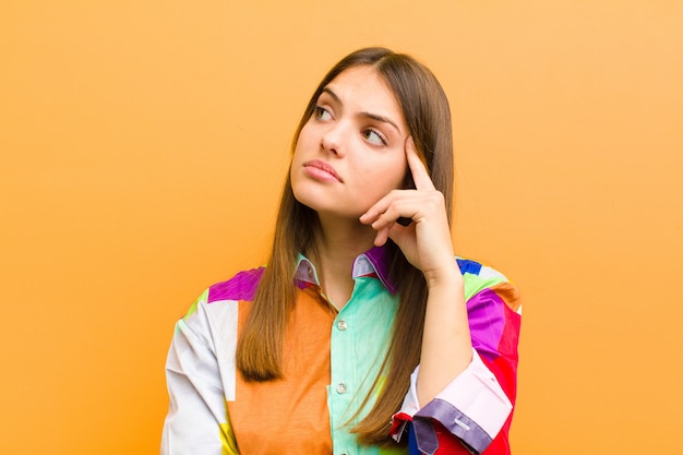 woman with a concentrated look, wondering with a doubtful expression, looking up and to the side