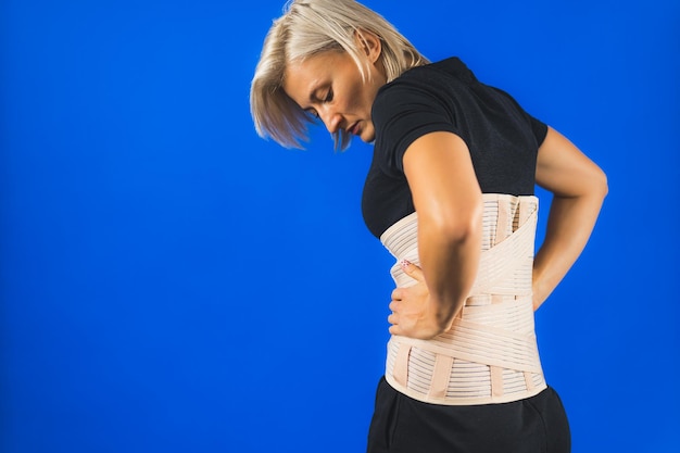 Woman with a corset on her back to support her back from pain in the back and spine medical concept