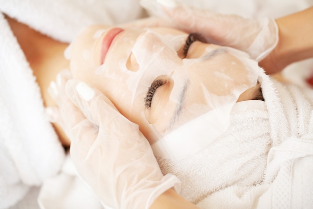 Woman with cotton face mask in beauty salon