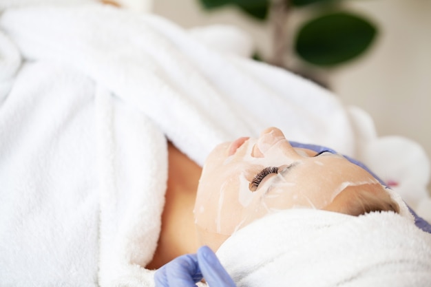 Woman with cotton face mask in beauty salon