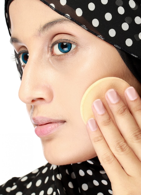 Woman with cotton pad applying face powder