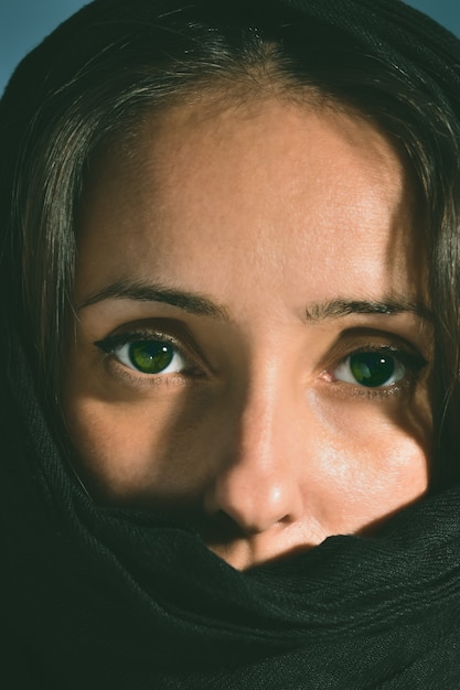 Woman with covered face with green eyes looking to the camera