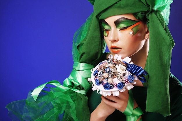 Woman with creative make up holding a bouquet of jewelry