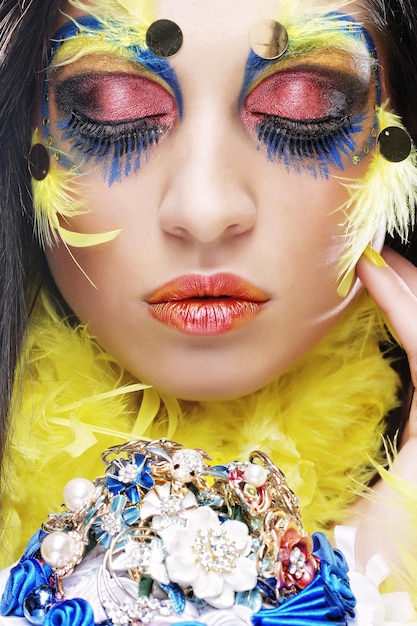 Woman with creative make up holding a bouquet of jewelry