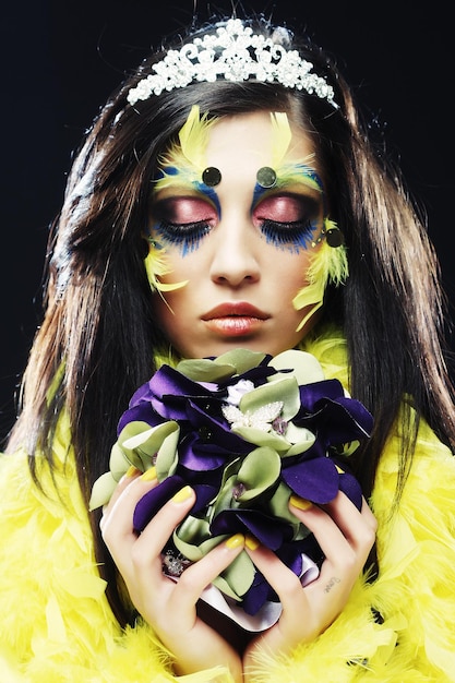 Woman with creative make up holding a bouquet of jewelry