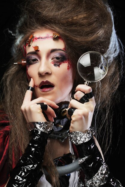 Woman with creative make up holding a magnifying glass