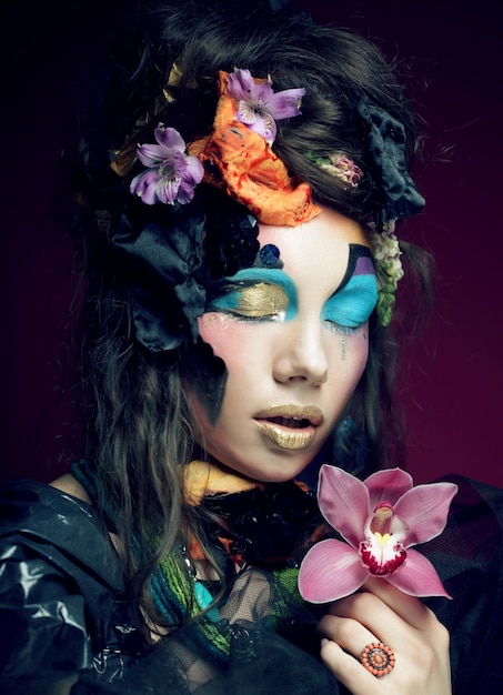 Woman with creative make up holding pink flower