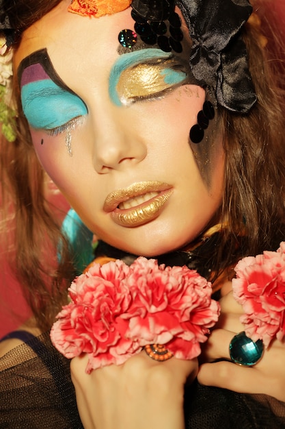 Woman with creative make up holding pink flower