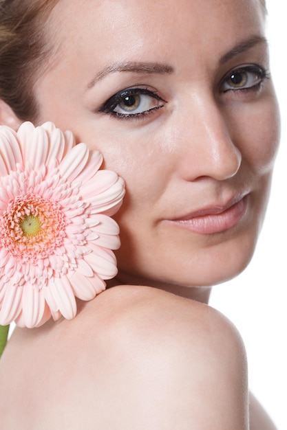 Woman with creative makeup with a gerbera flower on a white background International Women39s Day