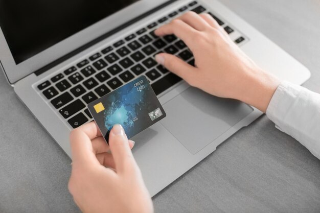 Woman with credit card and laptop at table closeup