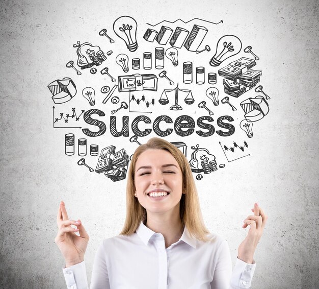 Woman with crossed fingers and success sketch on concrete wall