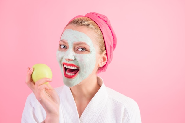 Woman with cucumber mask on face eats apple beauty treatments facial clay maskspa treatments health