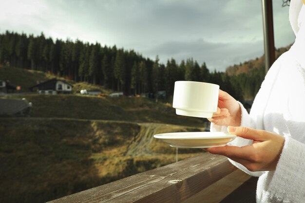 Donna con una tazza di caffè sul balcone nella stazione sciistica