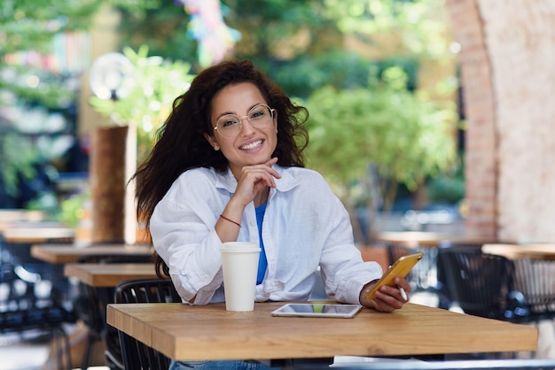 아침에 야외 카페에서 커피 한 잔을 들고 일하는 여성