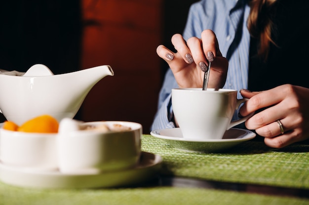 熱いお茶を片手にレストランに座っている女性がアロマティーを飲む女の子が休憩する瞬間を楽しむ