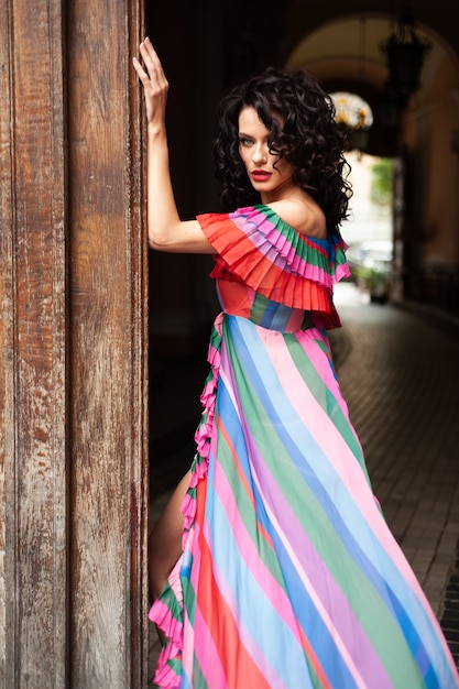 woman with curled dark hair in a summer dress in the city