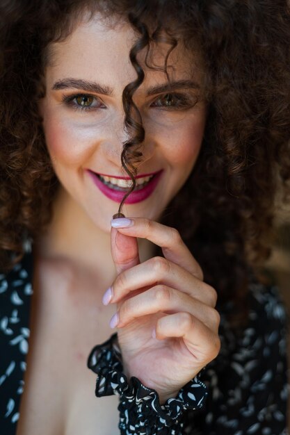 Foto una donna con i capelli ricci e un top nero con un rossetto rosa