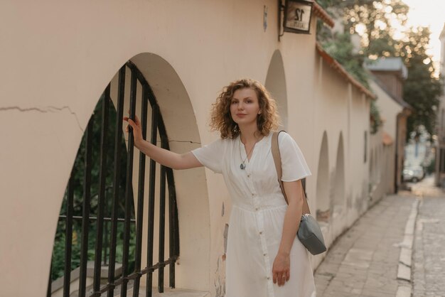 Photo a woman with curly hair is holding on to a bar of a lattice in an old town