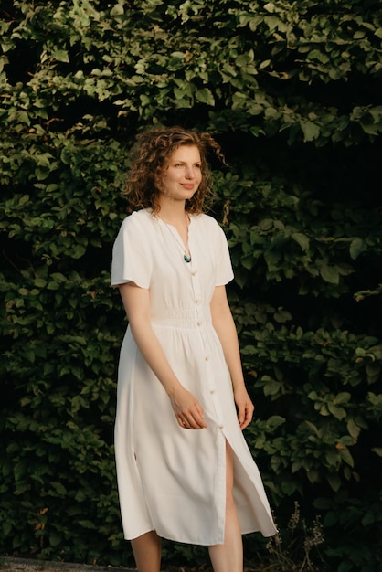 Photo a woman with curly hair is posing in the garden in the evening