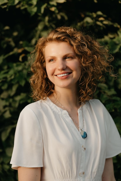 A woman with curly hair is posing in the park at the sunset