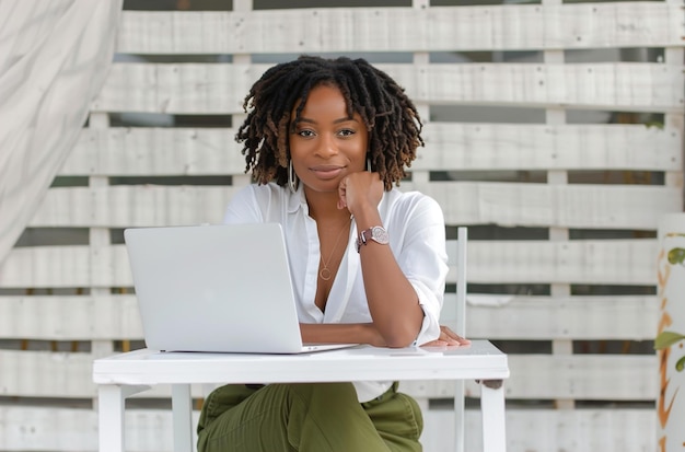 A woman with curly hair is sitting at a table with a laptop in front of her