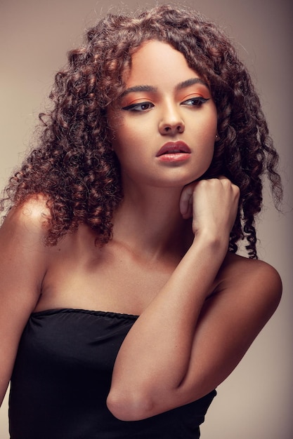 Woman with curly hair in profile holding both hands close to her chest with a sweet gaze