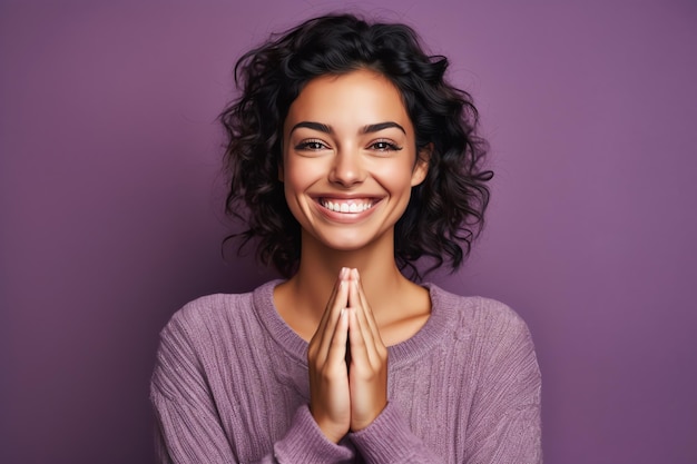 A woman with curly hair smiles and hands clasped in prayer