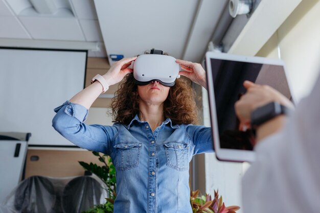 Foto donna con i capelli ricci che si prova il vr in ufficio