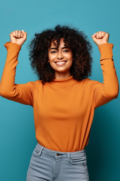 Woman with curly hair wearing orange shirt and grey pants with her arms in the air Generative AI