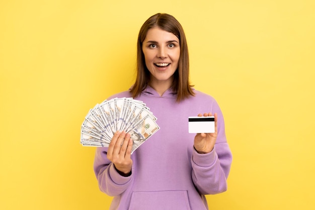 Woman with dark hair holding fan of dollars banknotes and credit card earning money banking