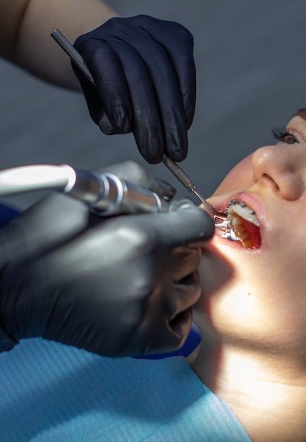 A woman with dental braces visits an orthodontist in the clinic in a dental chair