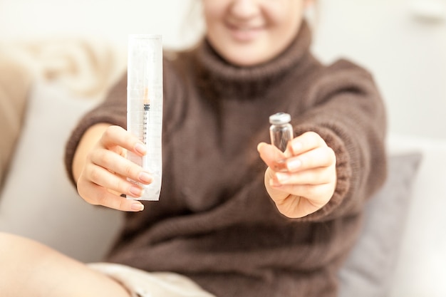 Woman with diabetes holding unpacked syringe and ampule in hands