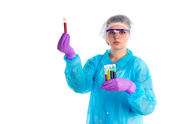 The woman with different tubes is showing some red liquid in a tube on a white background.