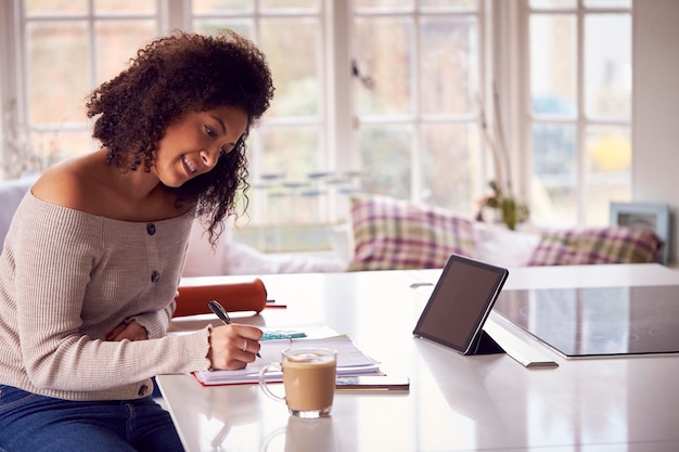 Woman With Digital Tablet Working From Home On Kitchen Counter