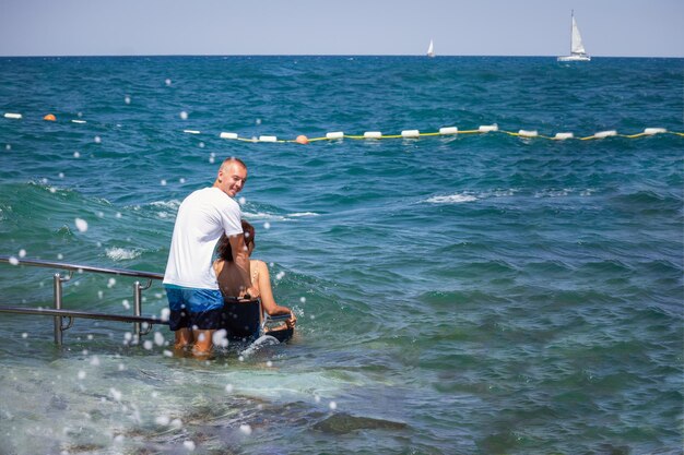 Woman with disability on wheelchair at accessible beach goes swimming