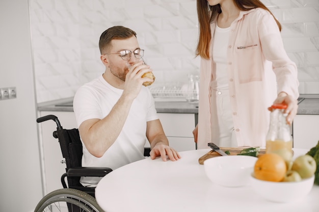 Woman with disabled man in wheelchair having breakfast together at home.