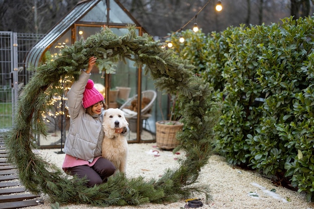 裏庭でクリスマス リースに犬を持つ女性