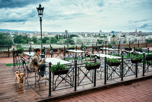 Woman with the dog in the empty cafe terrace