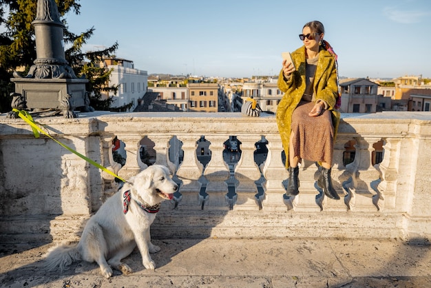 犬を持つ女性は、古いローマの街の美しい街並みを楽しんでいます