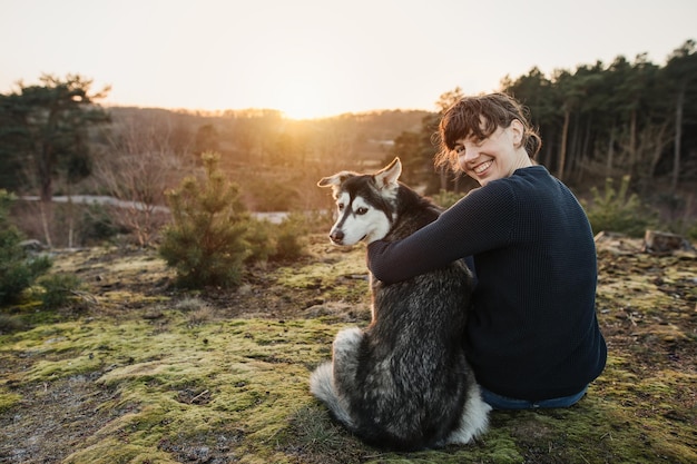夕暮れの場で犬を連れて行く女性