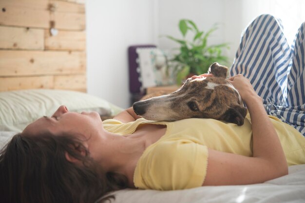Photo woman with dog lying down on bed at home