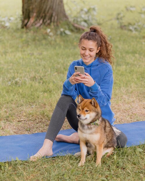 Woman with a dog in the park does sports or fitness on a yoga mat a european woman with curly