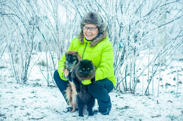 Woman with dog Pekingese and cat in winter park