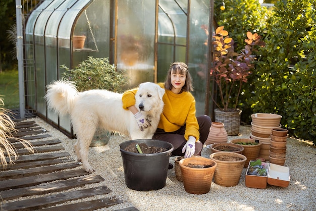 庭で犬の植物の花を持つ女性