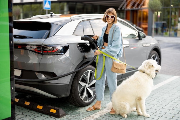 Woman with dog pulling a charging plug out of her ev car