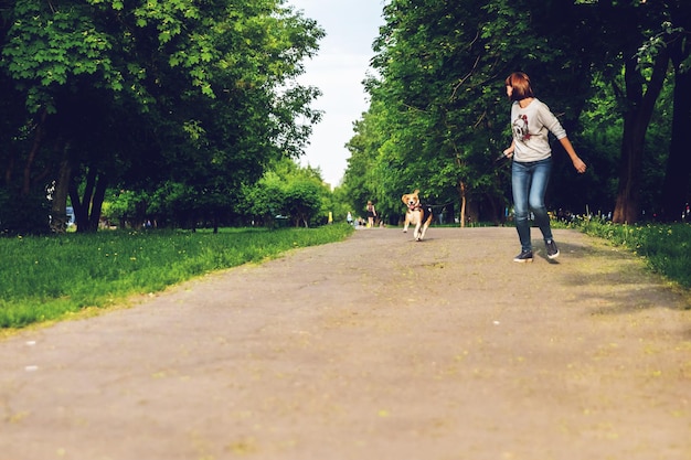 Photo woman with dog running on road against trees in park